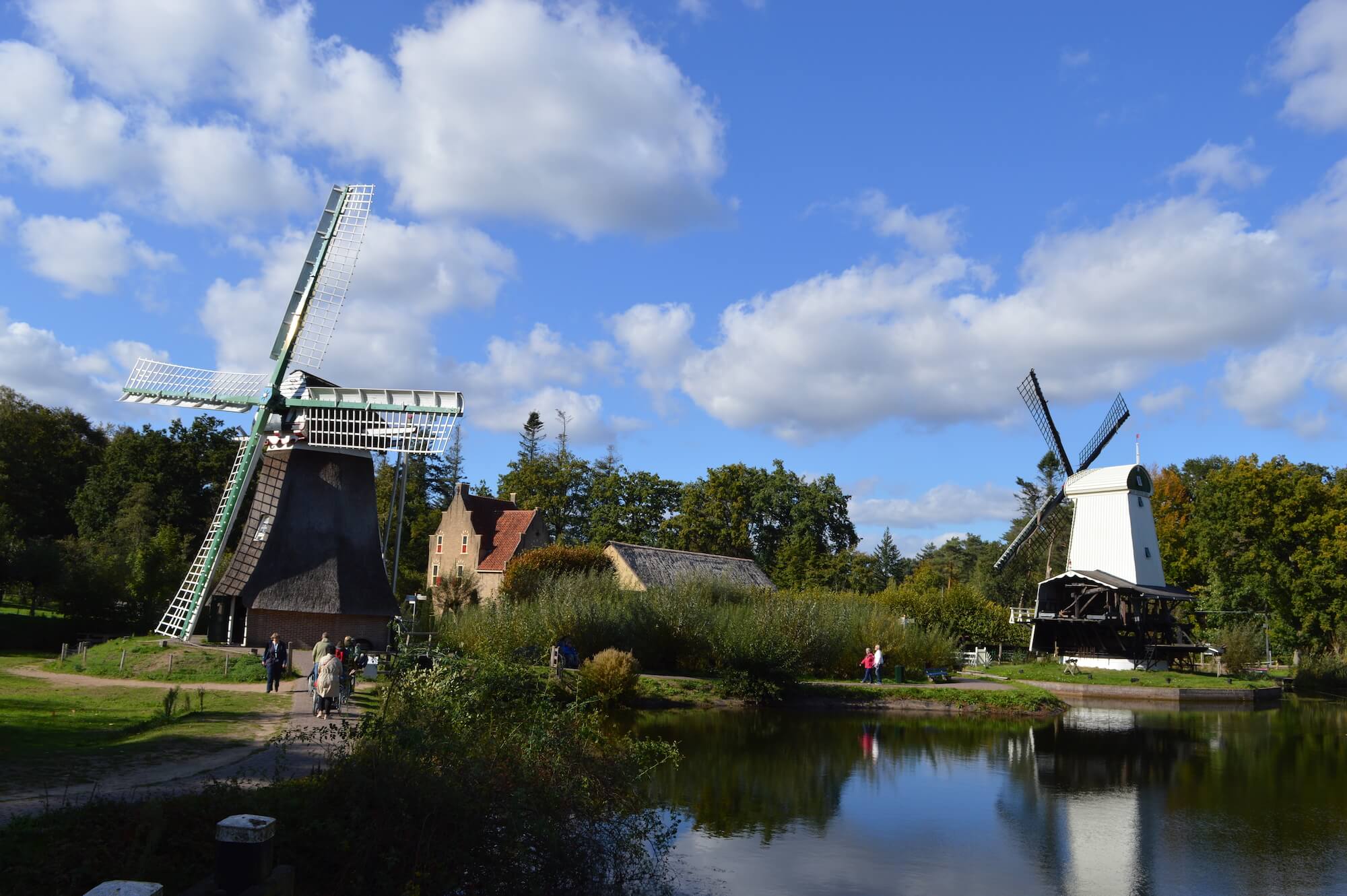 Landscape picture in the open air museum Arnhem, featuring multiple windmills and a blue sky with some small clouds.